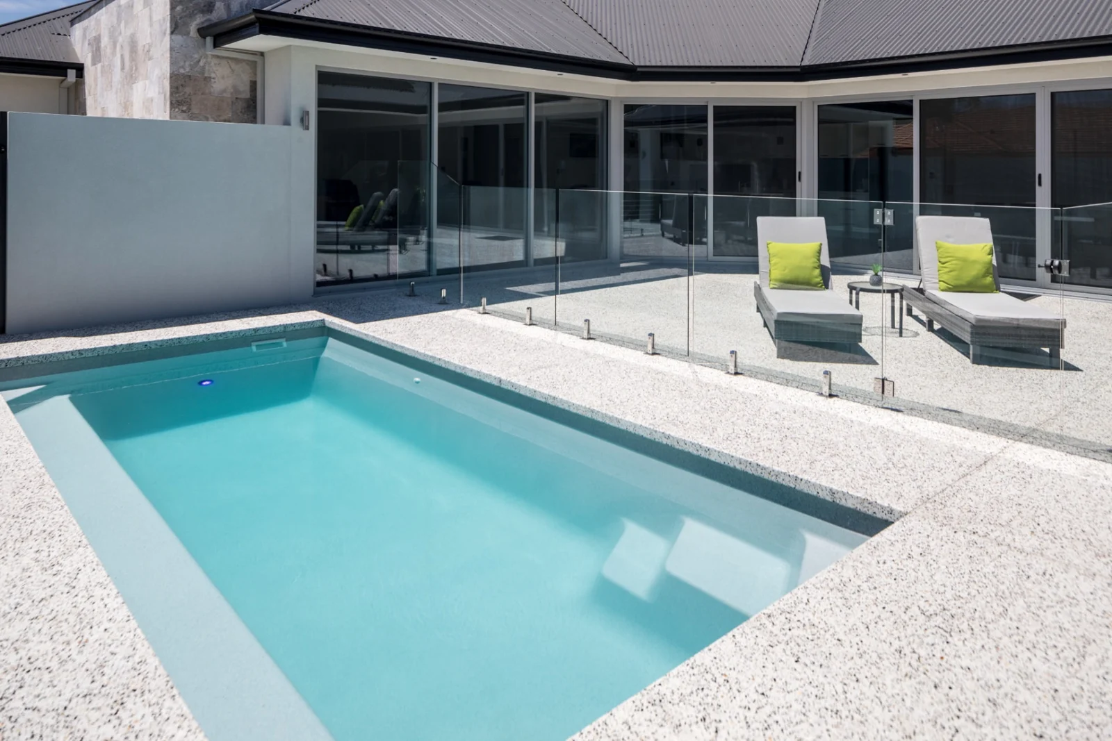 Completed Entertainer 7m fibreglass pool with entry steps, glass fencing and poolside loungers