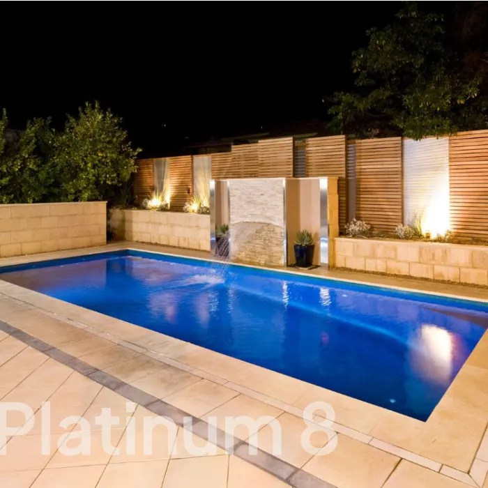 Platinum 8m fibreglass pool illuminated at night with a water feature