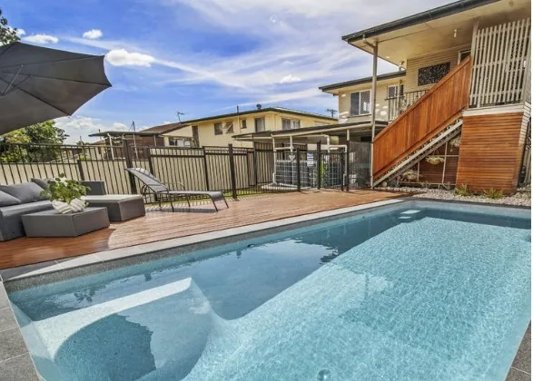 Platinum 9m fibreglass pool beside a timber deck and raised Queenslander home
