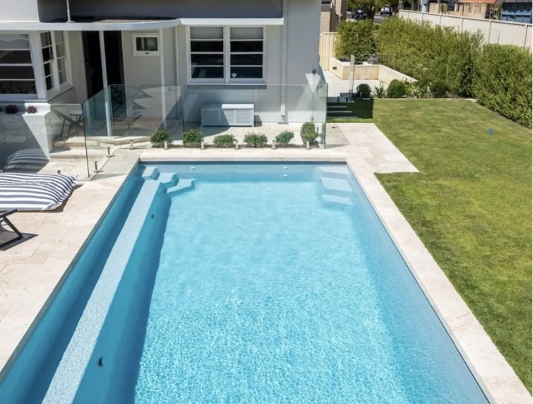Dolphin 10m fibreglass pool with a full-length bench seat, entry steps and paved surrounds