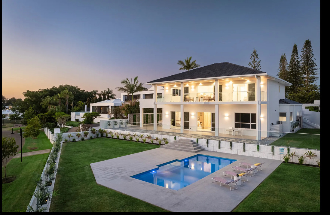 Luxury rectangular fibreglass pool beside modern waterfront home at twilight